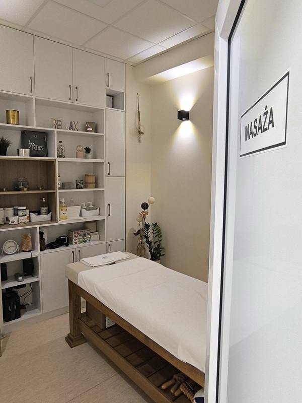 Sala za masažu — drveni sto za masažu, polica sa preparatima i natpis Masaža na vratima